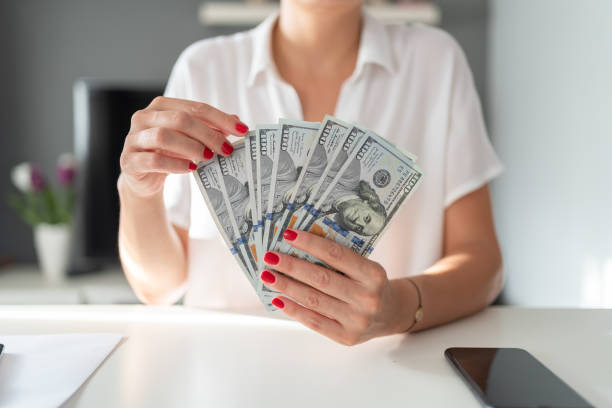 Woman hands holding dollar bills after accepting a cash offer