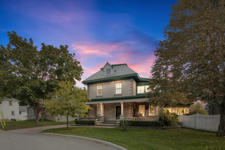 a house with full grown trees during a sunset