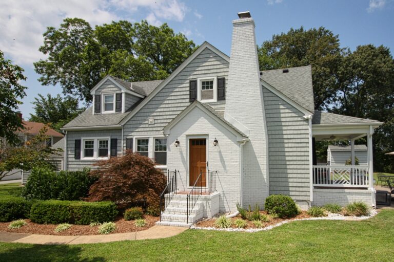 a gray house with white porch and brown door
