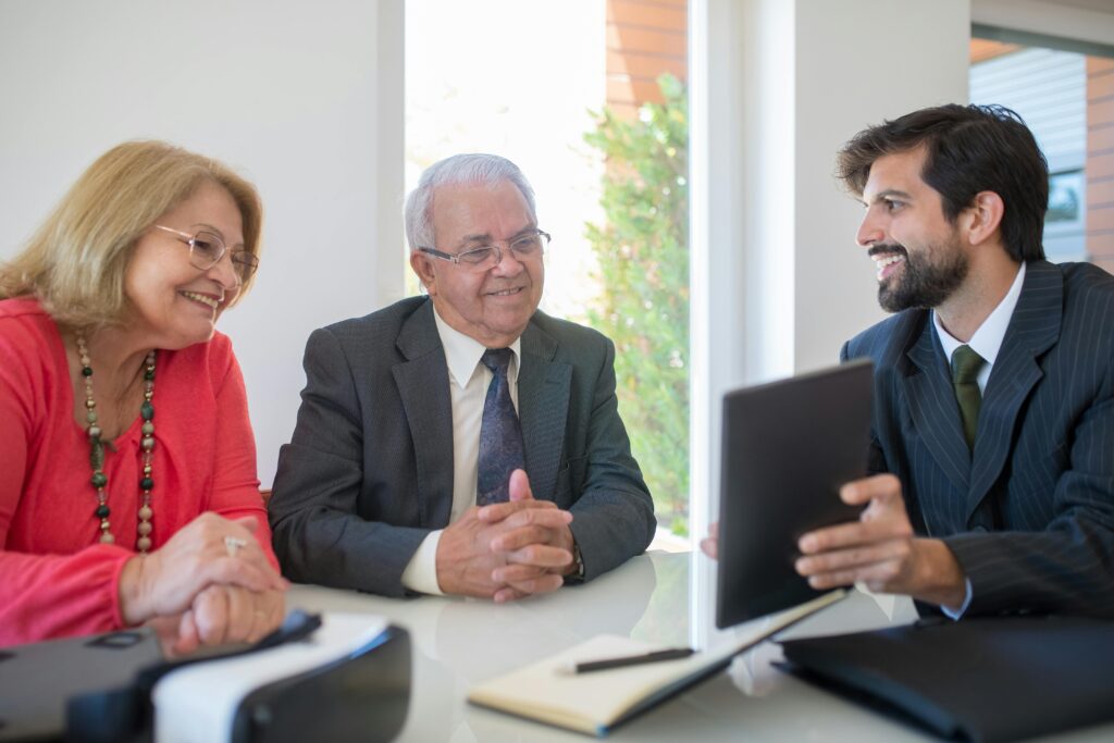 a man in black suit showing a tablet to a couple