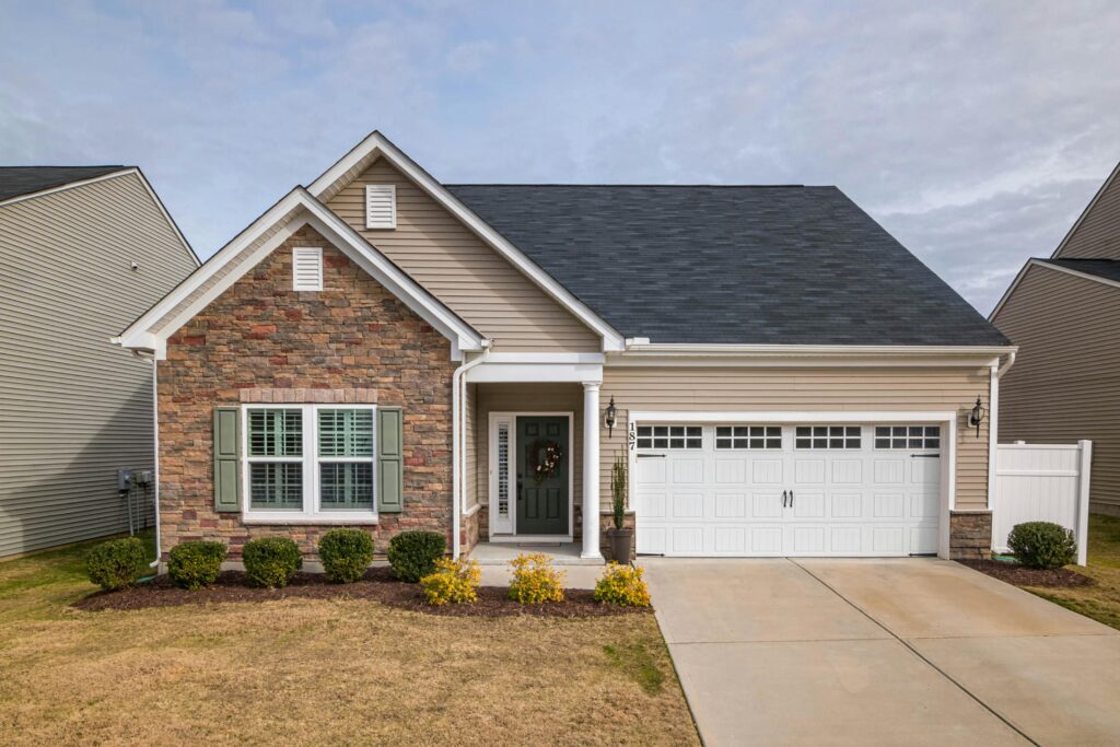 a brick house with attached garage and spacious front yard