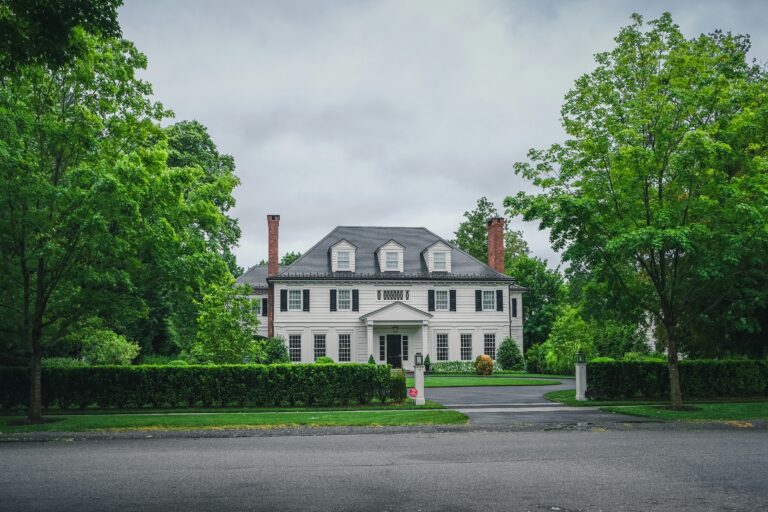 white and brown conrete house near green trees during daytime