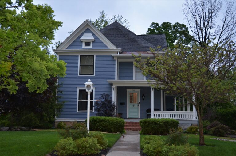white and gray house near green trees during daytime