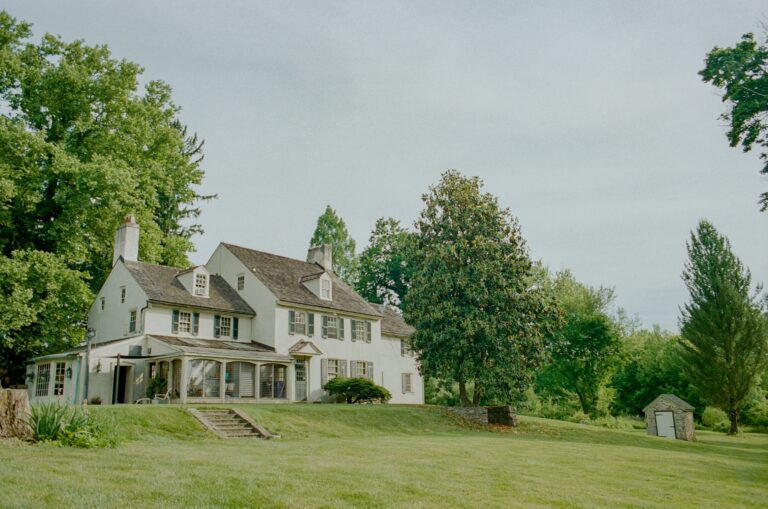 a large white house sitting on top of a lush green field