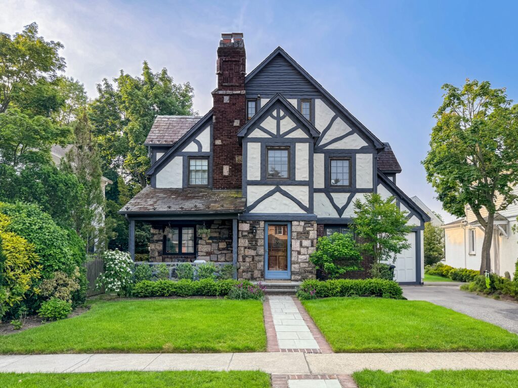 a charming tudor style house with a beautiful yard