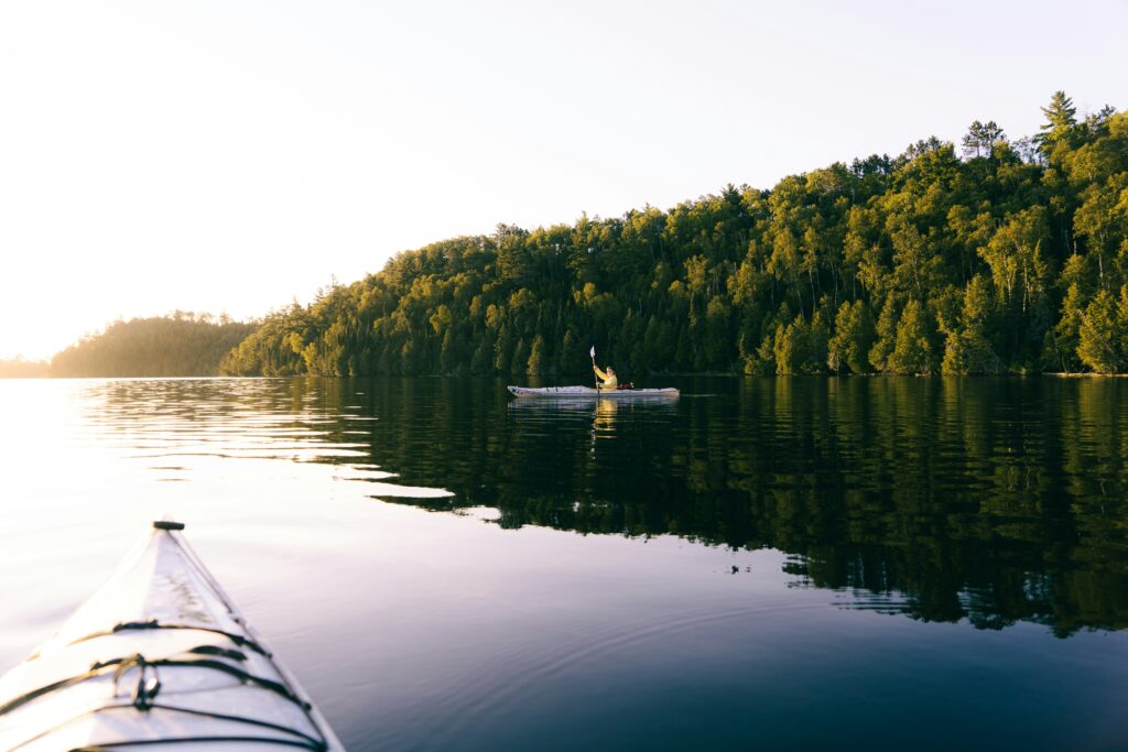 a person paddling a kayak on calm lake