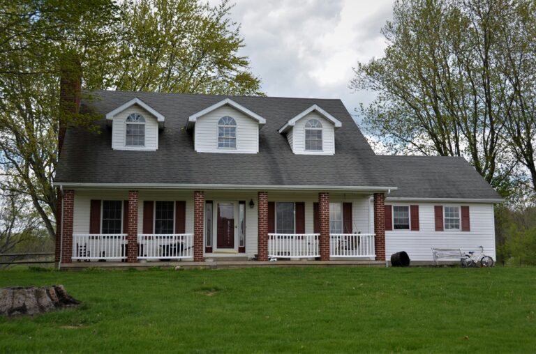white and gray wooden house near green trees during daytime