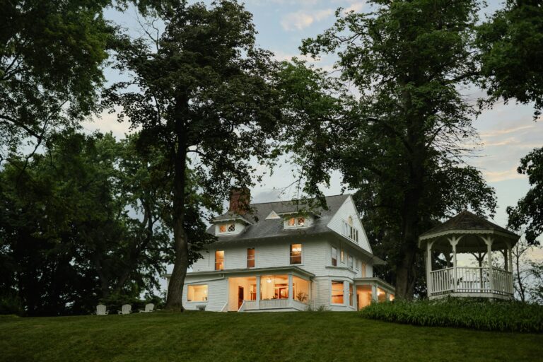 a large white house on top of a lush hillside