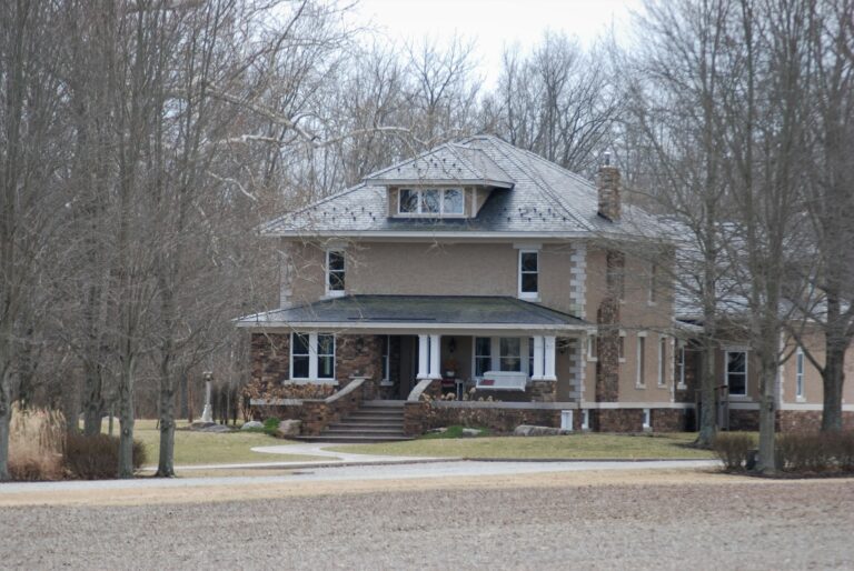 a large brown house surrounded by trees and grass