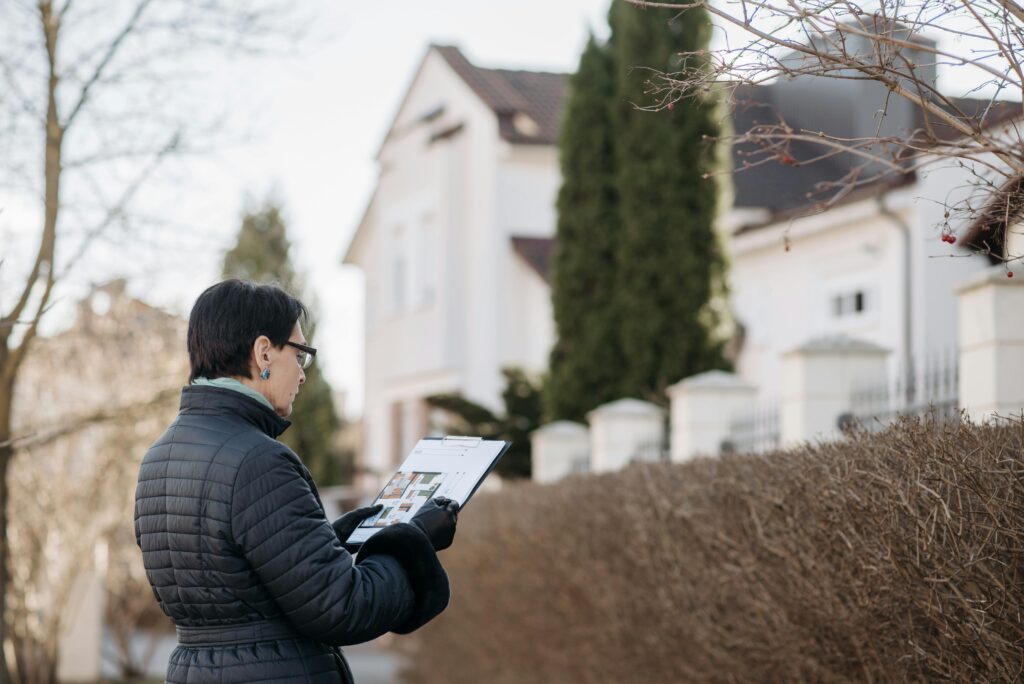 a woman standing on the street while holding a house plan