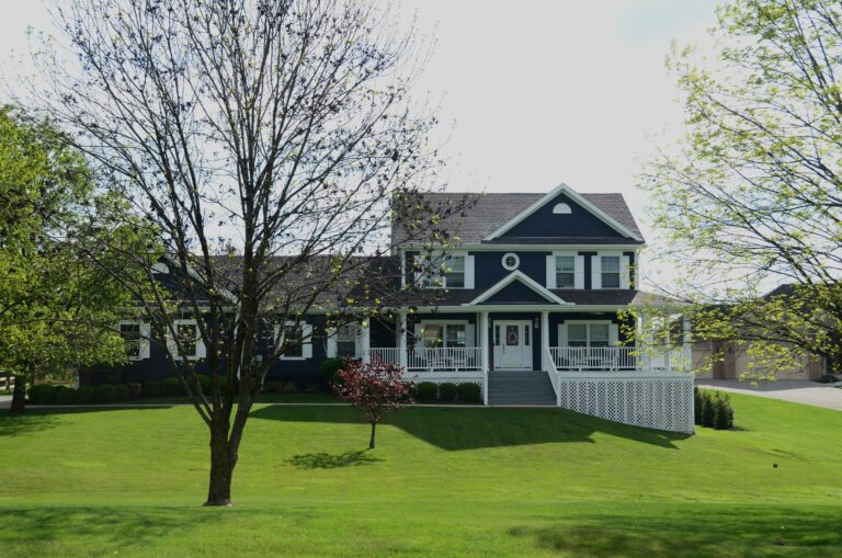 a blue and white modern country home with a huge porch