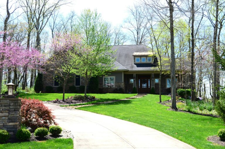 a house with driveway and trees in front