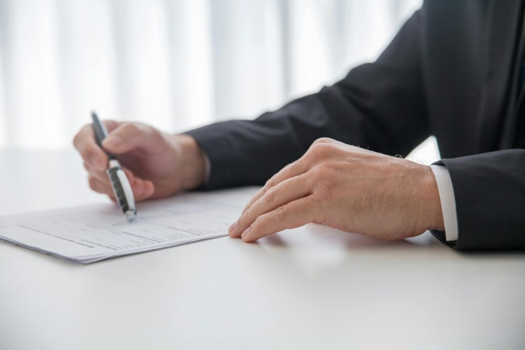 a person holding a pen and paper on a white table