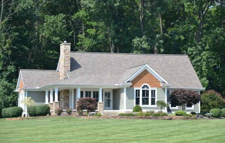 a beautiful house stands before a lush forest