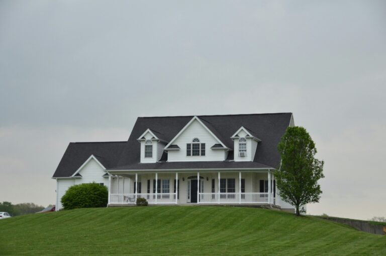 a white house sits on top of a green hill