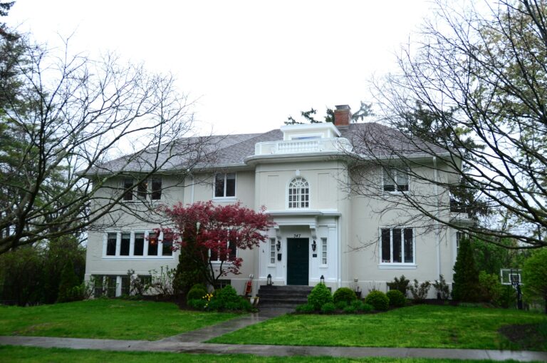a white house with trees and bushes in front