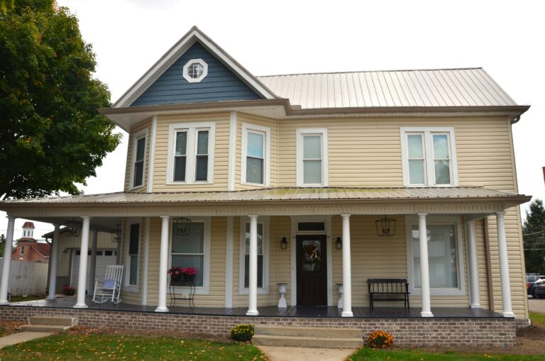 two story frame farmhouse in blue yellow and white