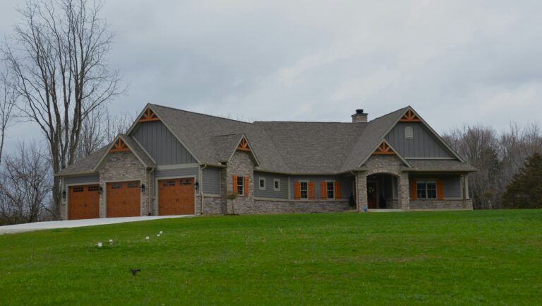 a large brick house with two garages on a grassy hill